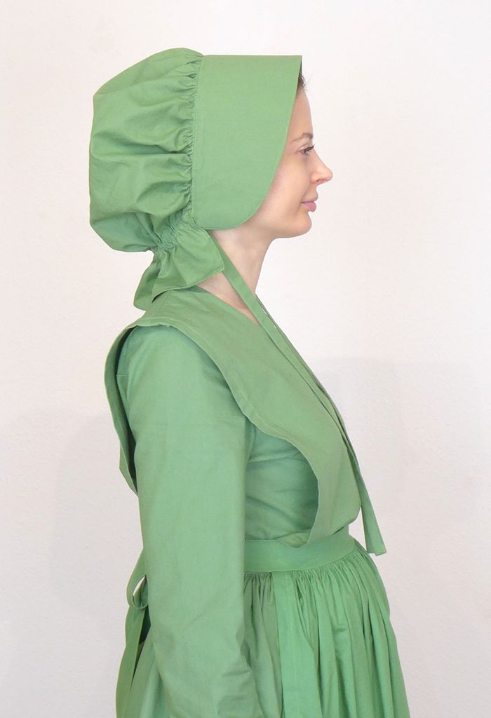 Side view of woman in a plain cape dress wearing a bonnet