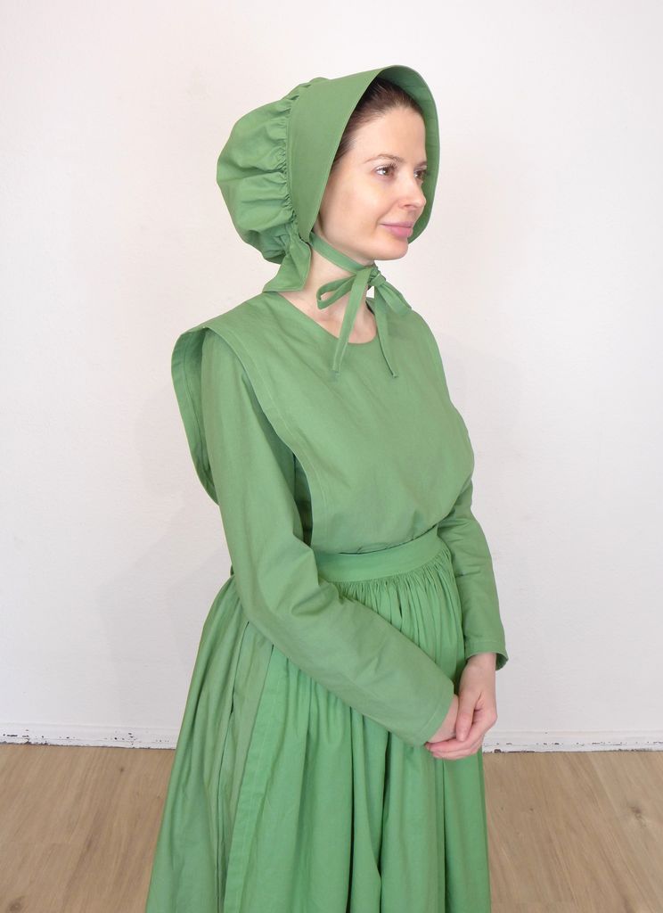 Front view of woman in a plain cape dress wearing a bonnet